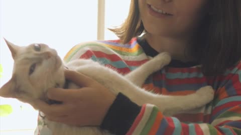 A woman petting and talking with her cat