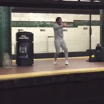 A woman in grey sweatsuit dances on subway station