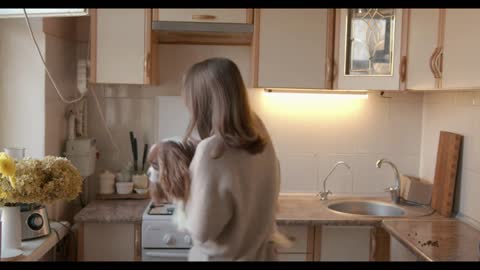 Cute dog sitting in the arms of a young woman with his head resting on her shoulder