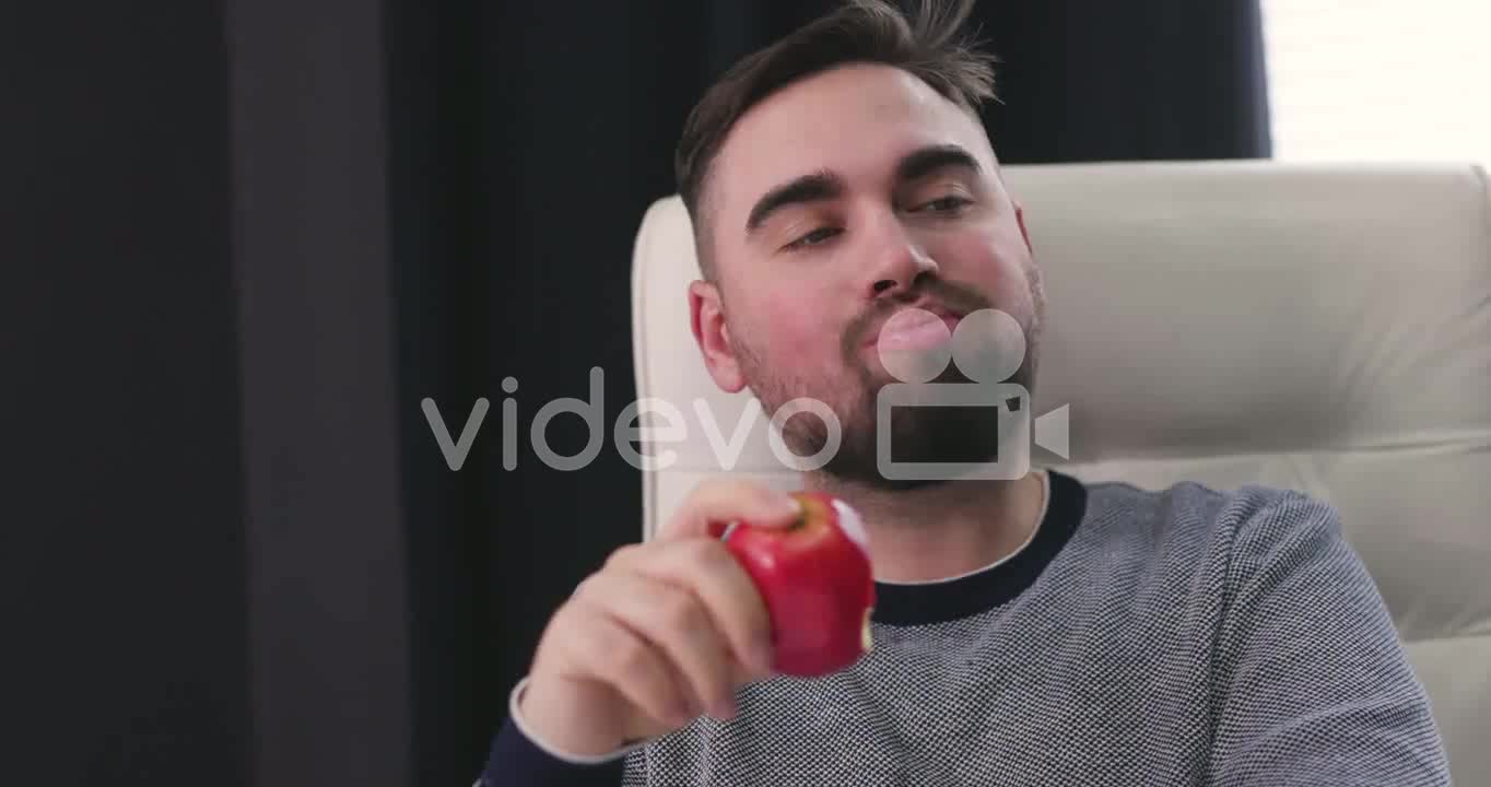 Hungry Man Sitting At Desk And Eating A Red Apple