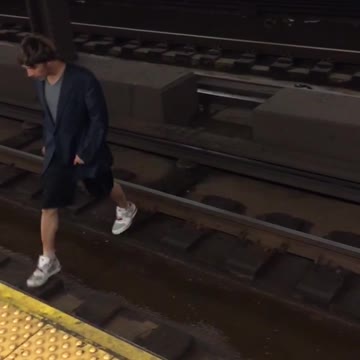 Guy black hoodie white shoes walks across tracks onto opposite platform