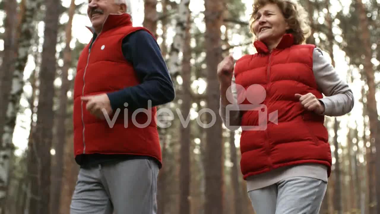 Happy Senior Couple Running Together In The Forest