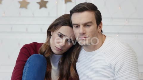 Portrait of Sad Couple Watching Video in Living Room