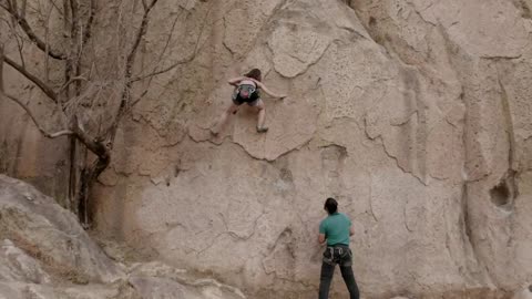 Female mountaineer climbing a huge rock