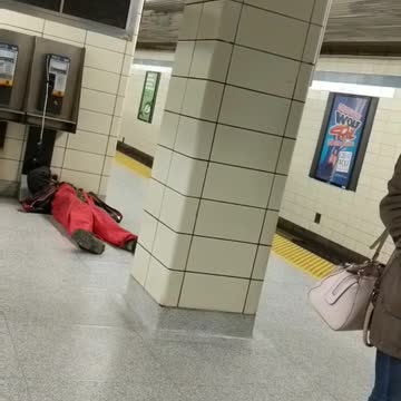 Guy in red laying next to payphone on subway platform