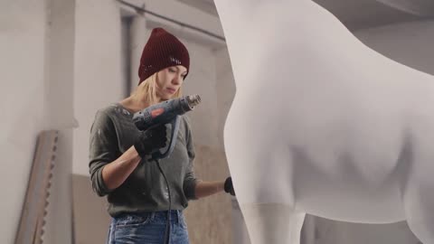 Female artisan in casual clothes and hat drying white paint