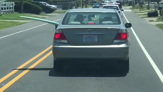 Silver car driving with blue surfboard out of driver rear passenger window