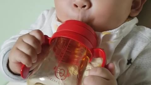 This is a video of a baby drinking water using a straw cup.