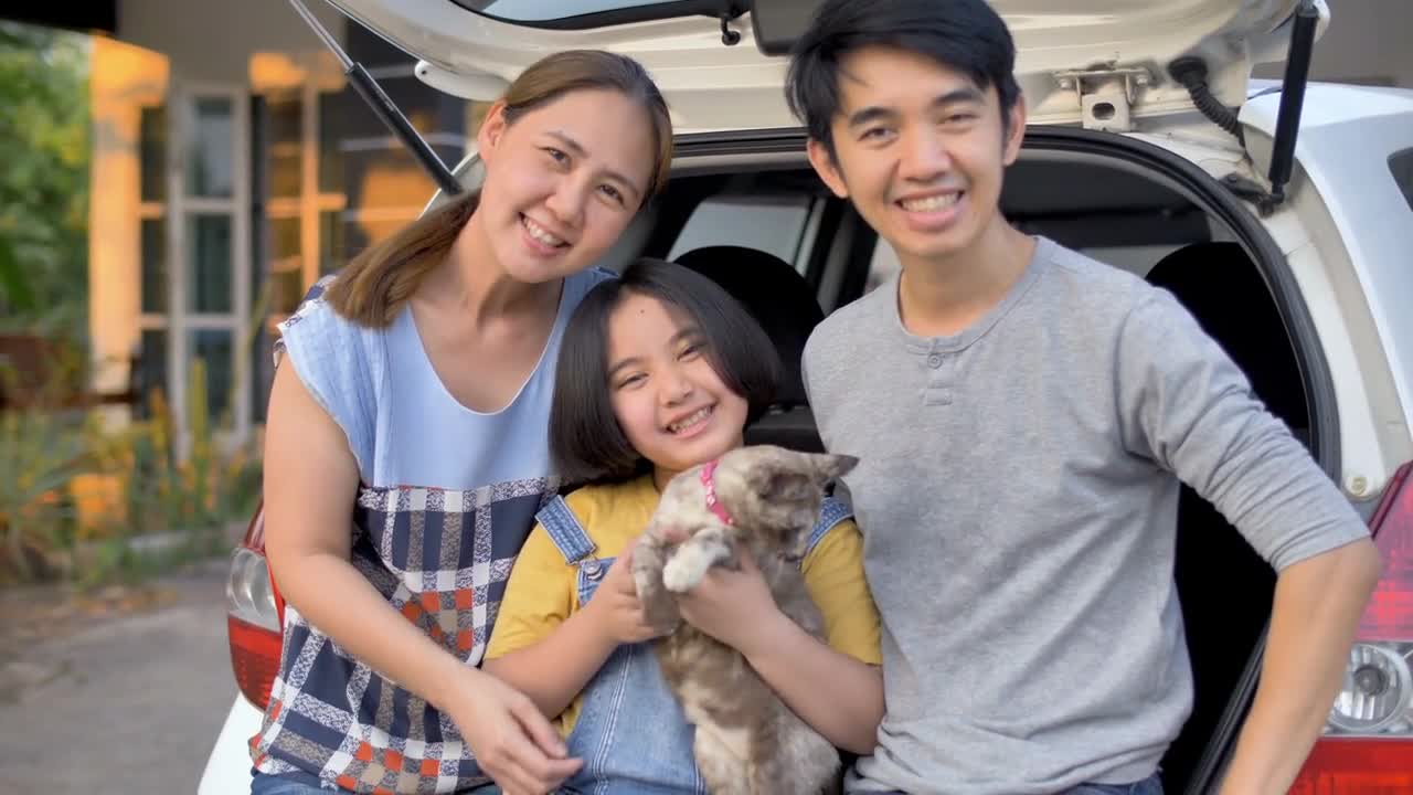 Happy family sit on the car and play with cute kitten