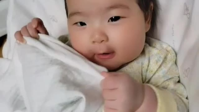 A smiling baby playing with a blanket