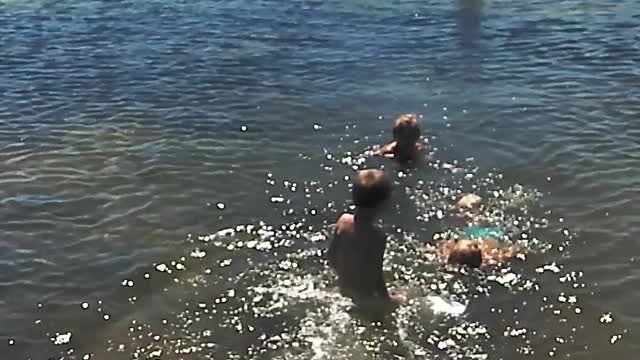 A child jumps into the water from the small bridge