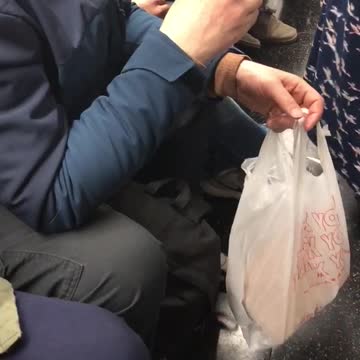 Old hat man eats bread food out of plastic grocery bag