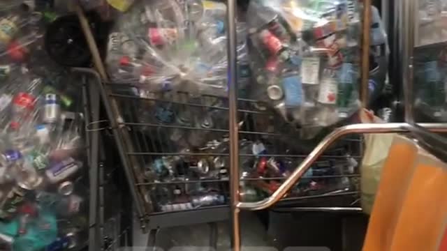 Subway train filled with dozens of bags and shopping cart full of aluminum soda cans