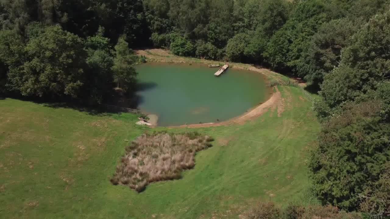 Drone Shot Flying Through Brick Arch to Reveal a Scenic Lake On Edge of Woodland