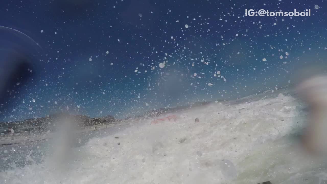 Guys red canoe get knocked over by wave beach