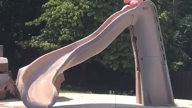 Girl slides into pool with drink