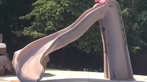 Girl slides into pool with drink