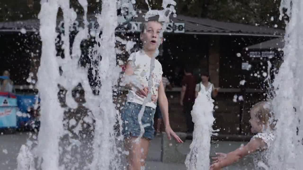 Kids play under water fountain