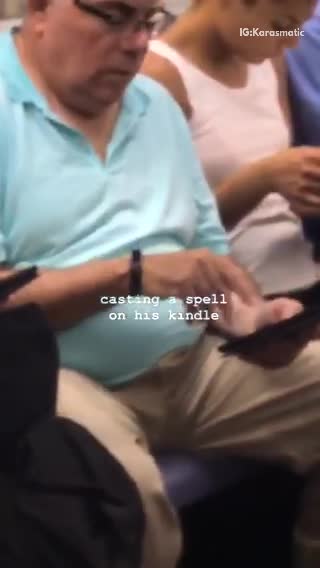 Casting a spell on his kindle man in blue shirt holding tablet on train