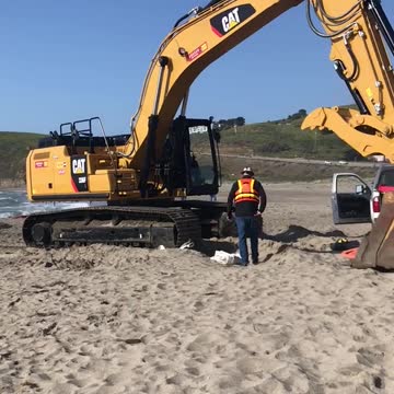 Tractor on beach to help sailing boat stuck on sand