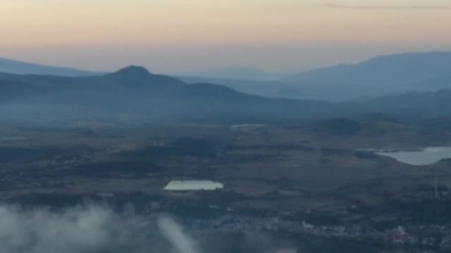 Flying over a landscape with mountains during sunset