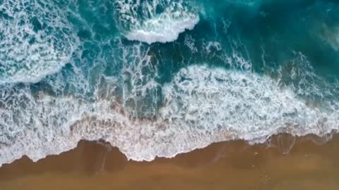 Foamy ocean waves rolling and coming on a sand beach. Aerial top down shot, 4K enjoy with ocean