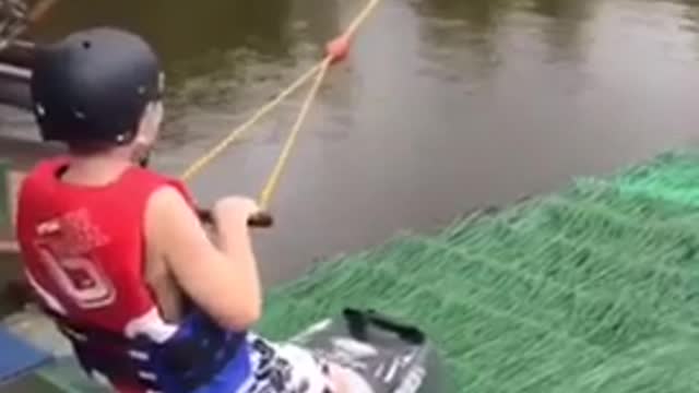 Boy kneeling on red ski pulled by rope
